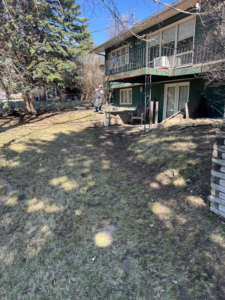 A lawn care worker using a blower to clear debris from a lawn for Top Cut Lawn Care and Snow Removal in Minot, ND.