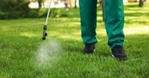 A lawn care professional spraying weed control treatment on a lawn by Tee Time Lawn Care Davenport, IA.