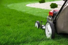 A lawnmower cutting fresh green grass, leaving neat stripes, demonstrating services by Love it Lawn Care in Butte, MT