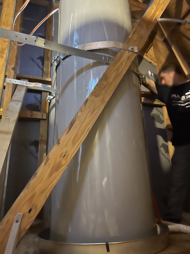 A leaking water heater in an attic with water collected in the pan, showing water damage by Plumb Pro in Mountlake Terrace, WA.