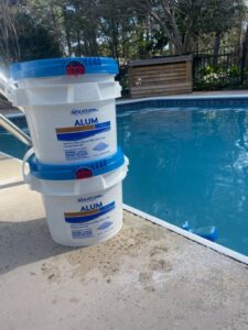 Buckets of Leslie's Alum pool clarifier by the poolside, used by Pool Services of Wilmington in Wilmington, NC.