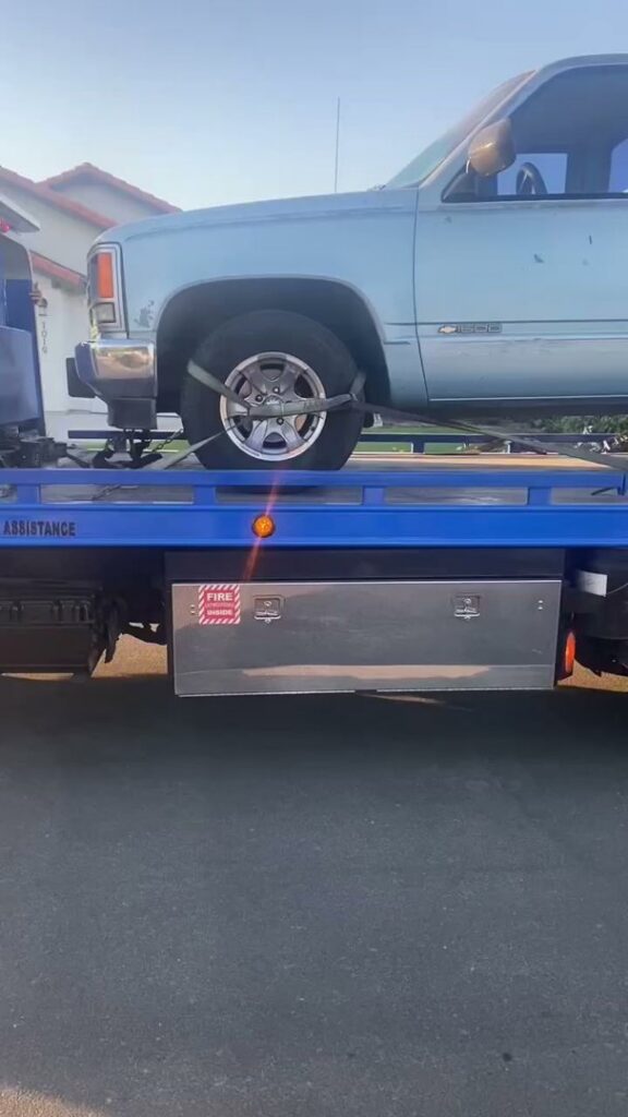 A light blue pickup truck securely loaded onto a flatbed tow truck by A&A Towing Services in Bakersfield, CA.