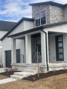 A modern home featuring light gray horizontal siding and elegant stone accents, completed by New Look Siding in Midvale, UT.