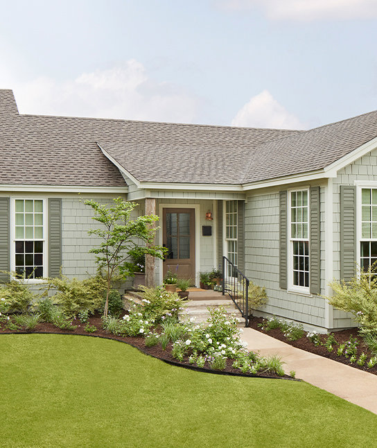 A beautiful home featuring light green shake siding and white trim, a project by Bushco Contracting LLC in Fresno, CA.