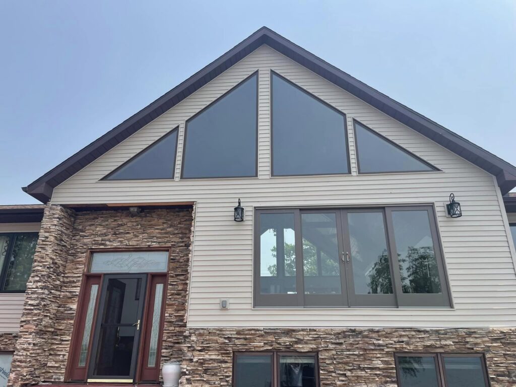 A house with light-colored siding and decorative stone veneer, showcasing work by Murphy Builders- Genesee County in Ossineke, MI.