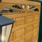 A close-up of a light wood garage door with decorative windows and panels by Advance Garage Door, Inc. in Fargo, ND.