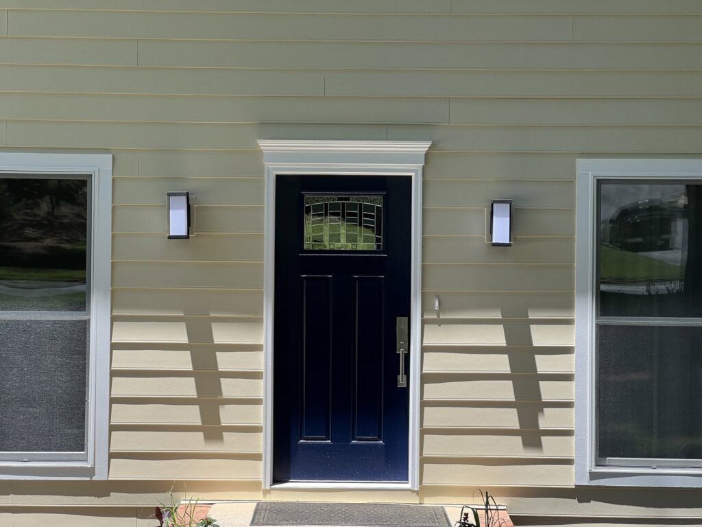 A house with new light yellow siding and a contrasting dark blue front door by HP Exteriors in Woodstock, GA