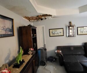 Living room with ceiling water damage and a dehumidifier for drying by ABC Cleaning and Restoration in Harvest, AL.