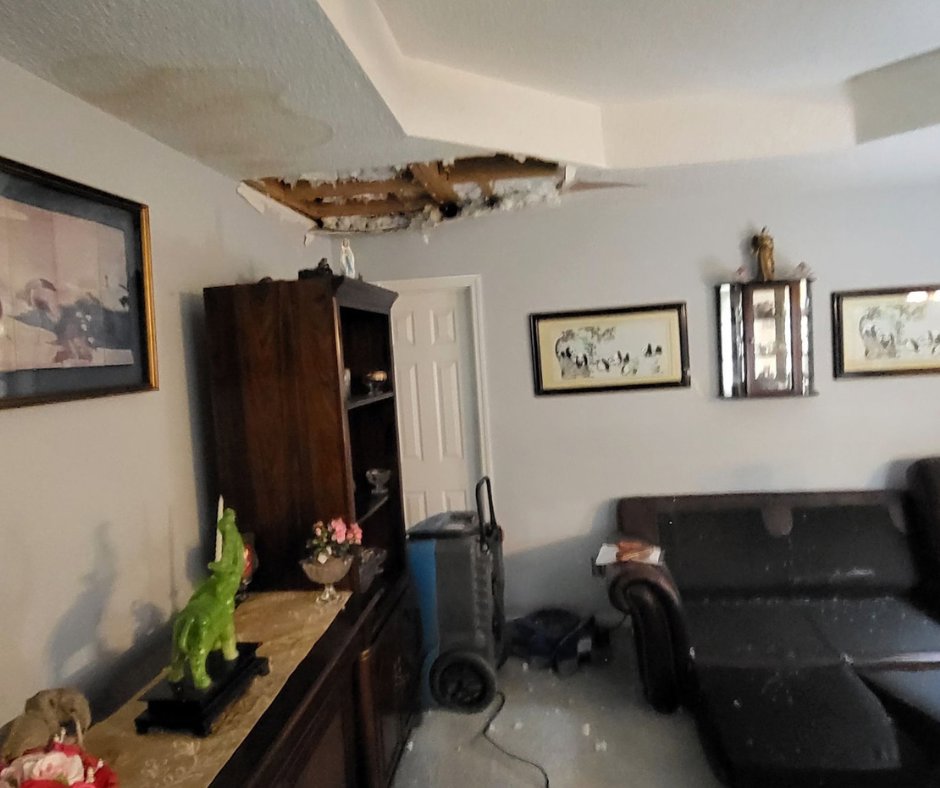 Living room with ceiling water damage and a dehumidifier for drying by ABC Cleaning and Restoration in Harvest, AL.