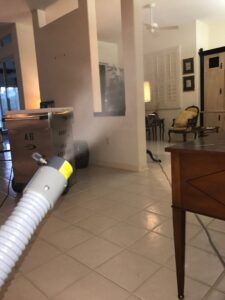 A living room being treated with a fogging device and large restoration equipment by Southcoast Cleaning Solutions & Restoration in Fall River, MA.
