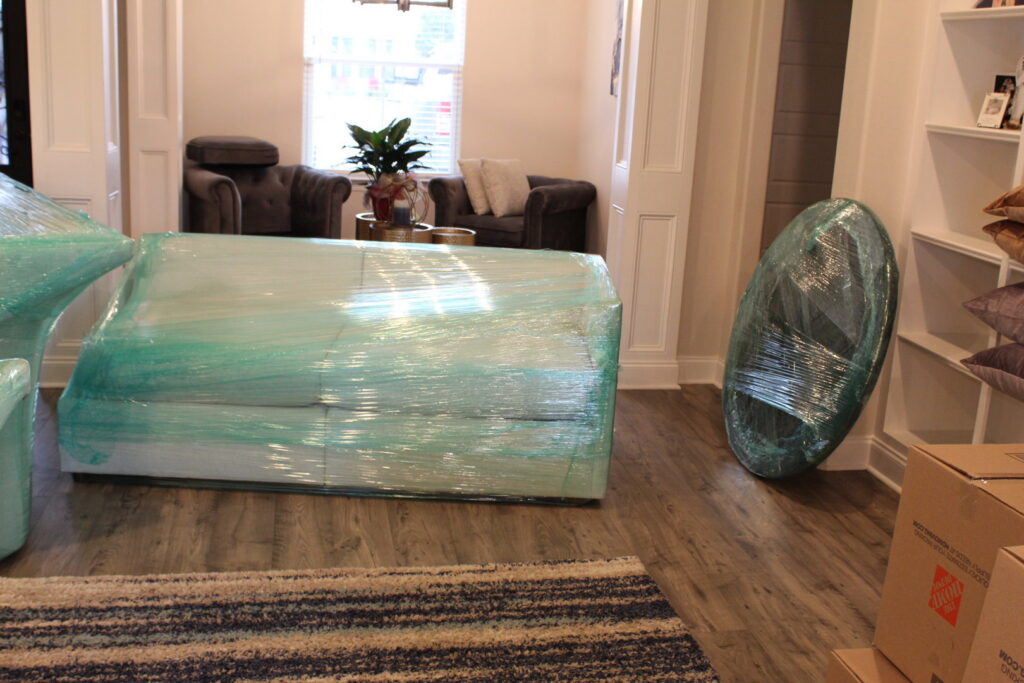 Living room furniture, including a sofa and mirror, meticulously wrapped for moving by Gifted Journey Movers in Gulfport, MS.