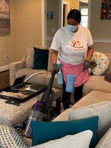 A house cleaner vacuuming a living room carpet for TAG Team Cleaning of West Hartford, CT