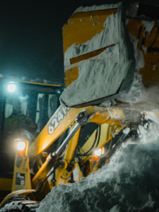 A close-up of a yellow loader bucket pushing a large pile of snow for Elcor Construction in Rochester, MN.