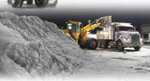 A front-end loader efficiently loading a large pile of snow into a dump truck for hauling by Appleton Snow Removal in Appleton, WI.