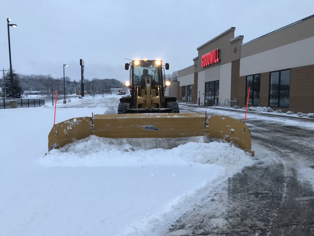 A front-end loader plowing snow from the Goodwill parking lot for Rochester Ground Lawn & Snow Services in Rochester, MN.