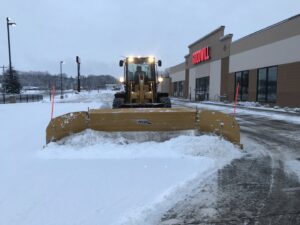 A front-end loader plowing snow from the Goodwill parking lot for Rochester Ground Lawn & Snow Services in Rochester, MN.