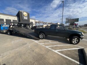 A dark green Toyota Tacoma pickup truck being loaded onto a flatbed tow truck by ABOD Towing LLC in New Orleans, LA.