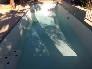 A long residential swimming pool being cleaned with a vacuum while partially filled by Bluemar Pool & Spa Services in North Las Vegas, NV.