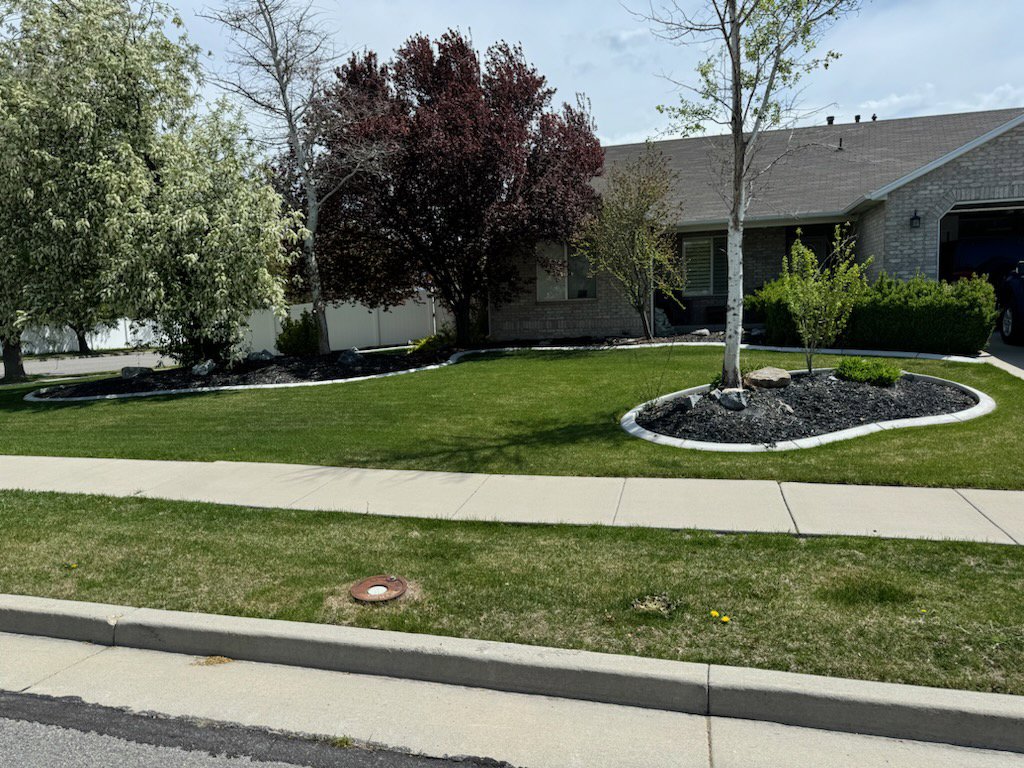 A lush green front yard with a manicured lawn and mulched garden beds by Lakeside Lawn Care in Sanford, NC.