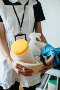 A Maid Brigade cleaner holding a caddy full of cleaning supplies, ready for a house cleaner job in Houston, TX.