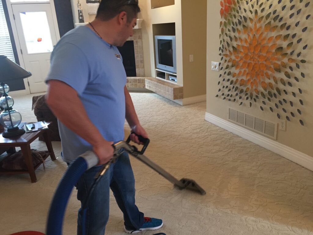 A man professionally cleaning a living room carpet for Happy Client Cleaning Services in Fort Collins, CO.