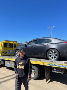 A man standing with a yellow flatbed tow truck from Terry's Auto Service and Towing, LLC, towing a car in Springfield, MO.