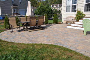 A manicured backyard lawn next to a paved patio area, showcasing services by Bailey's Lawn and Landscape in Smyrna, DE.