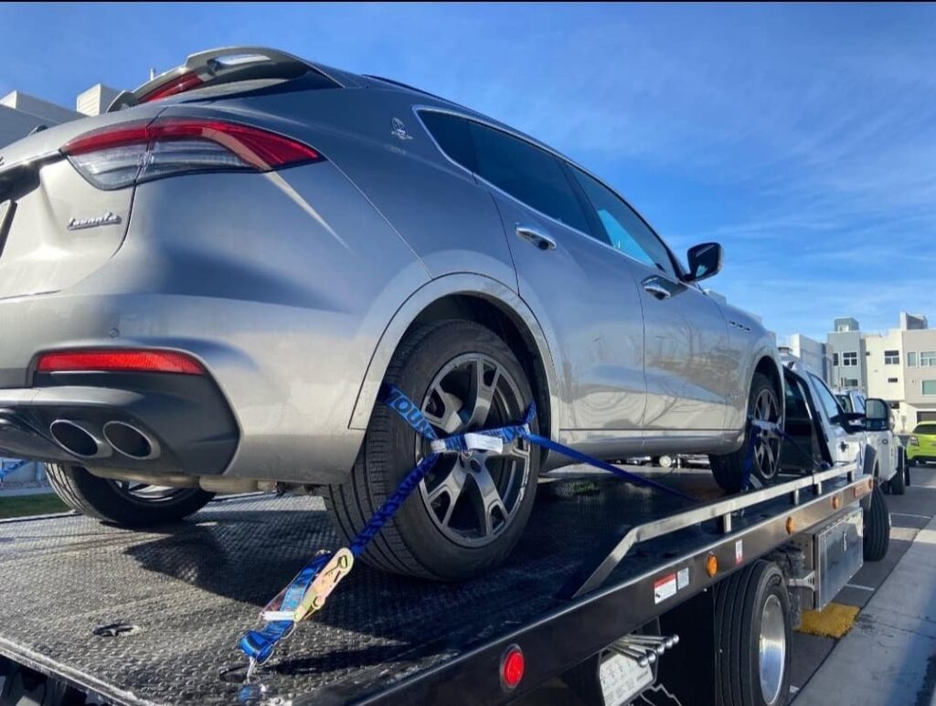 A grey Maserati SUV securely strapped onto a flatbed tow truck by 4 Wheel Towing in South Salt Lake, UT.