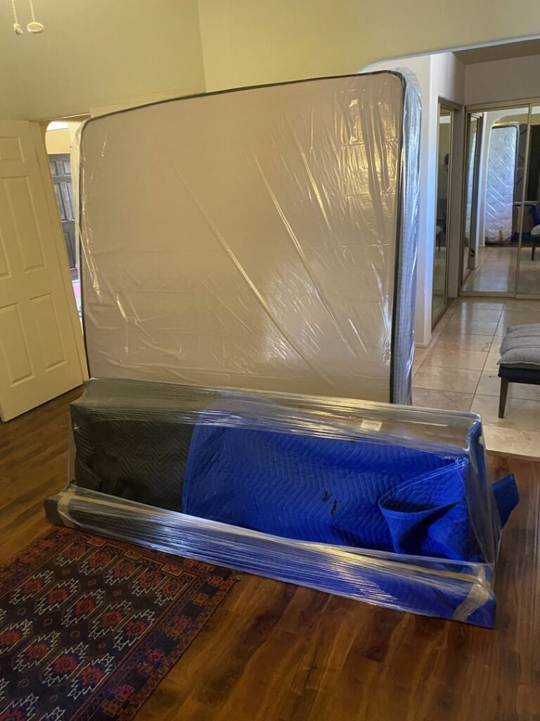 A mattress and other furniture wrapped in protective plastic and blankets, prepared by Moving Marvels in Tucson, AZ.