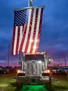 A McDowell Wrecker Service heavy-duty tow truck with an American flag at dusk in Springfield, MO.