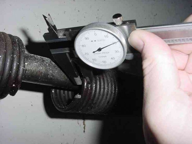 A hand measuring a garage door spring with a caliper for accurate replacement by Sandia Garage Door Repair in Albuquerque, NM