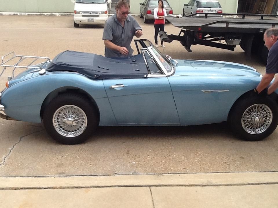 Two men preparing a vintage blue convertible car for towing with a Tow Jam flatbed truck in Dallas, TX.