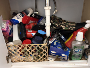 A cluttered bathroom cabinet before professional cleaning and organization by On Course Cleaning in Fayetteville, NC.