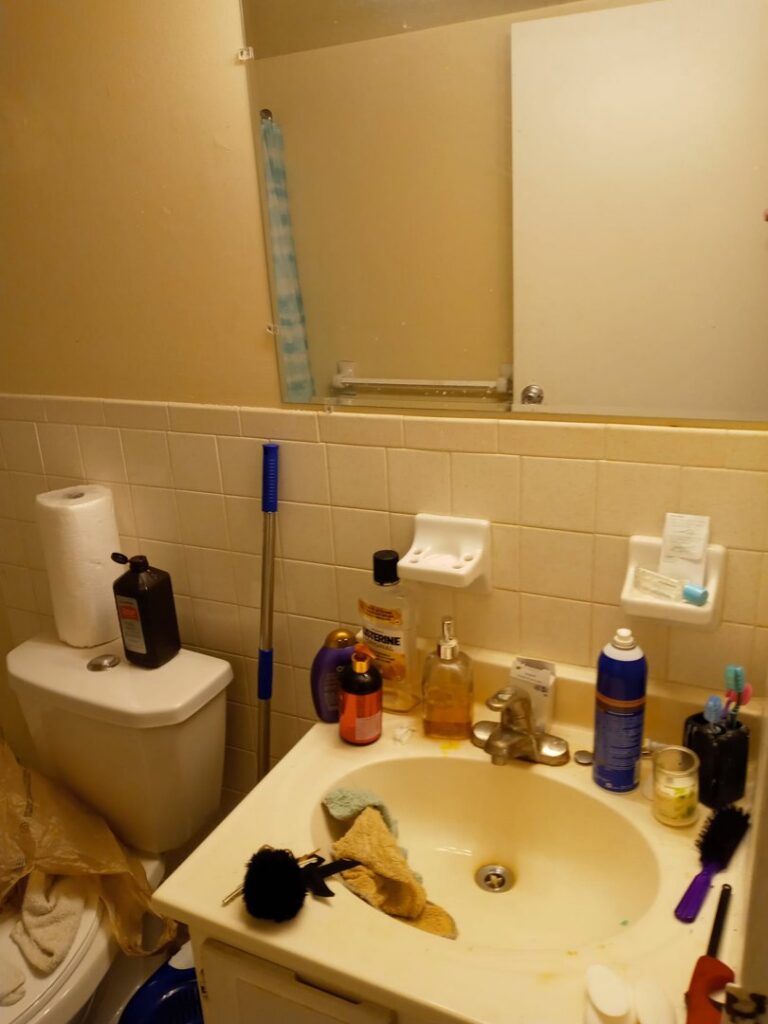 A cluttered and messy bathroom vanity before professional cleaning by Whole New World Cleaning Service, LLC in Wilmington, DE
