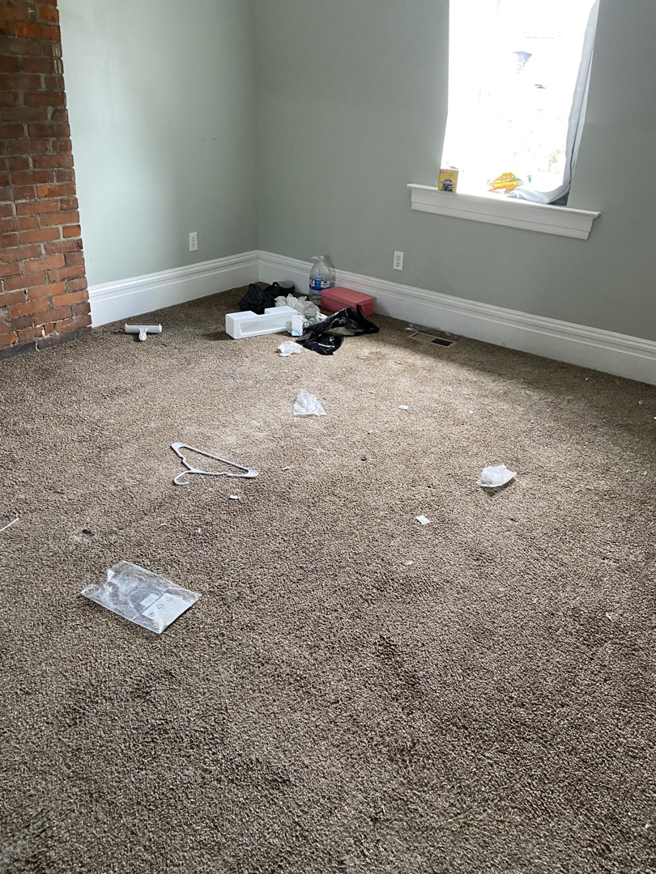 A messy carpeted room with debris on the floor, ready for professional cleaning by Starr's Sparkling Cleaning in St. Louis, MO