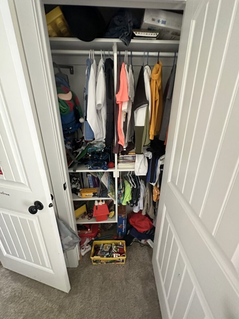 A cluttered closet filled with clothes and items, representing a "before" image for organization services by Groove-By-Nature Cleaning in Idaho Falls, ID.