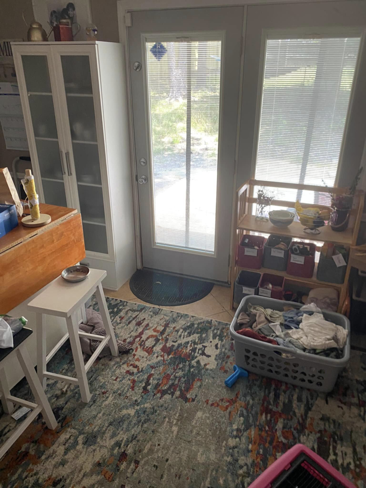 A messy kitchen and dining area with a laundry basket, showing a space ready for professional cleaning by EMarie Professional Cleaning Services & More in Little Rock, AR.