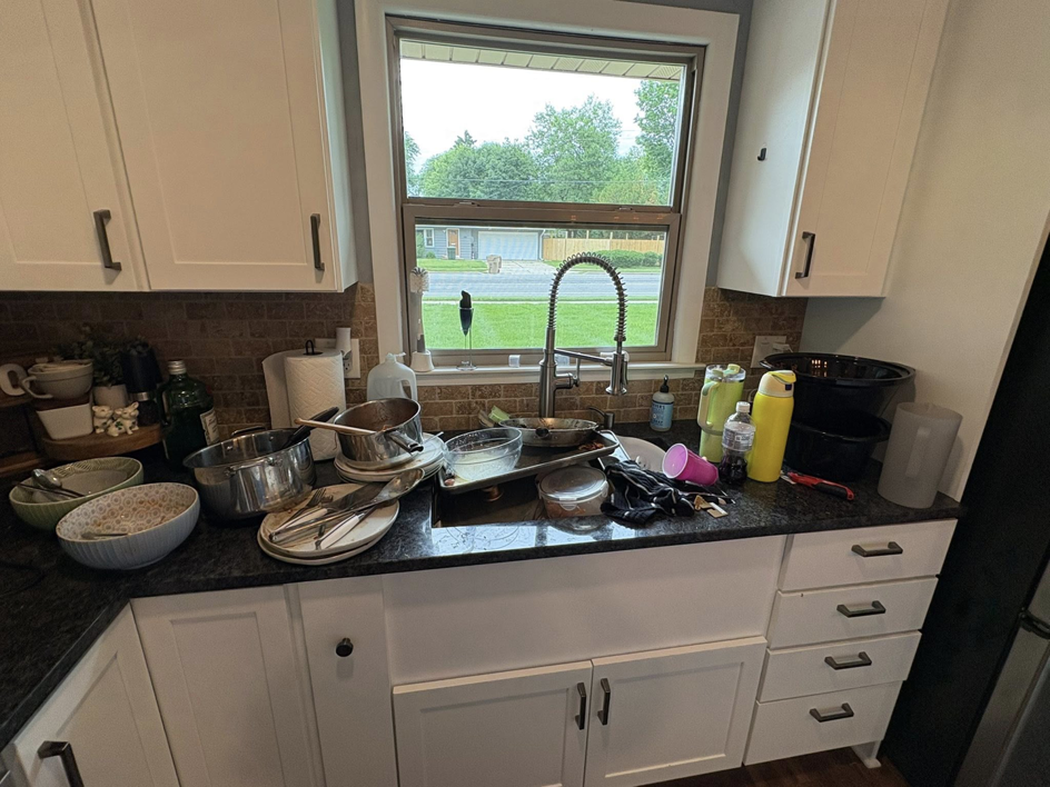 A messy kitchen sink filled with dirty dishes and pots before cleaning by Warm & Cozy House Cleaning in Madison, WI