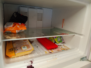 A messy refrigerator with food items and spills, showing the need for professional cleaning by KB Cleaning in Bozeman, MT.