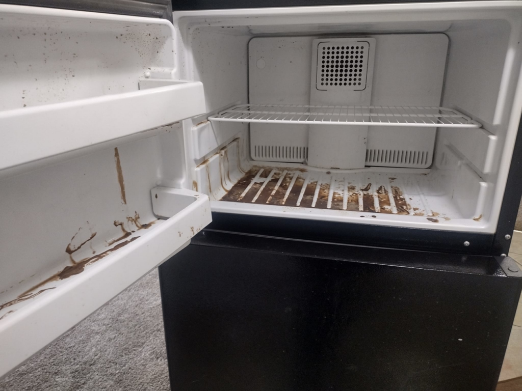 A messy refrigerator interior with spills and grime, ready for cleaning by By Grace Cleaning Solutions, LLC in Cincinnati, OH.