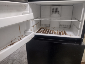 A messy refrigerator interior with spills and grime, ready for cleaning by By Grace Cleaning Solutions, LLC in Cincinnati, OH.