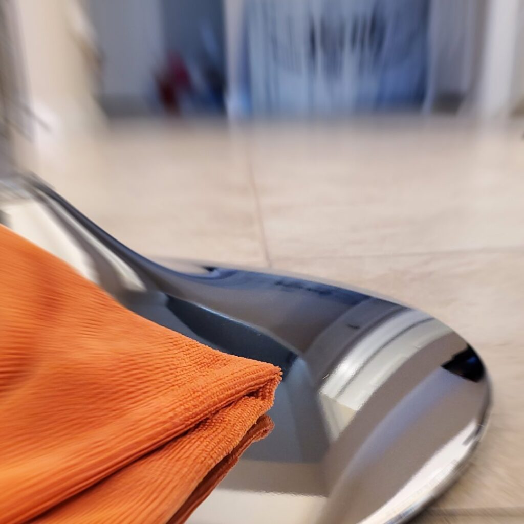 Orange microfiber cloth on a shiny surface, representing detailed cleaning by Rubber Gloves Residential Cleaning in San Antonio, TX.