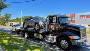 A Milan Towing inc. flatbed truck towing two SUVs on a sunny day in Milan, MI.