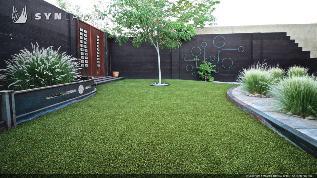 A modern backyard landscape featuring artificial grass and decorative plants by SYNLawn of New Mexico in Albuquerque, NM.