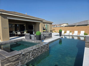 A modern backyard featuring a dark-tiled pool and integrated spa, built by Steve Breck Pools in Las Vegas, NV.