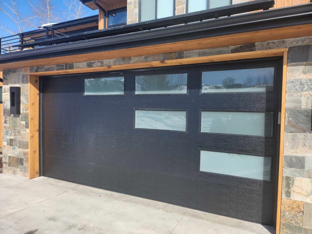 A modern black garage door with horizontal windows installed by Layton Doors in West Jordan, UT.