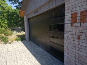 Modern black garage door installed on a brick house by Garage Doors & More in Bentonville, AR