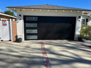 A modern black garage door with frosted glass panels, showcasing a completed installation by Lifetime Garage Door in Las Vegas, NV.