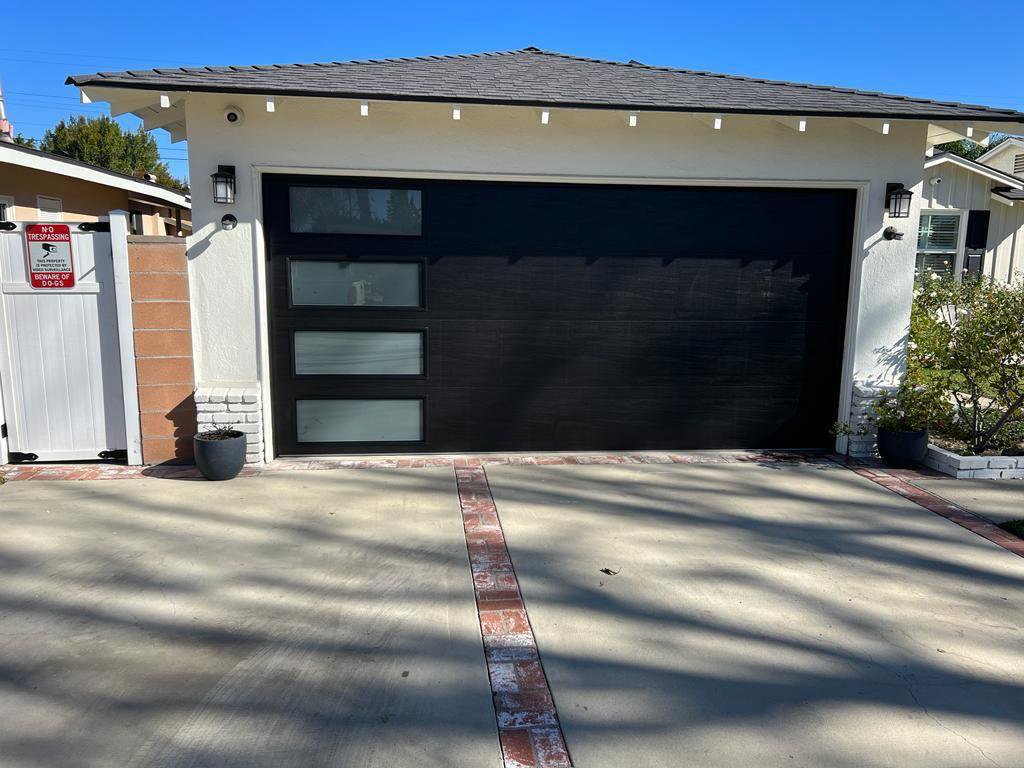 A modern black garage door with frosted glass panels, showcasing a completed installation by Lifetime Garage Door in Las Vegas, NV.