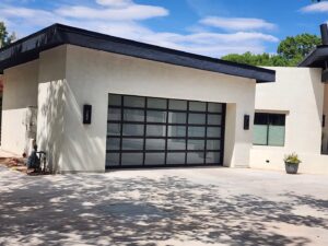 A modern house featuring a large black garage door with multiple windows, installed by Quality-Brand Garage Doors in Rio Rancho, NM.